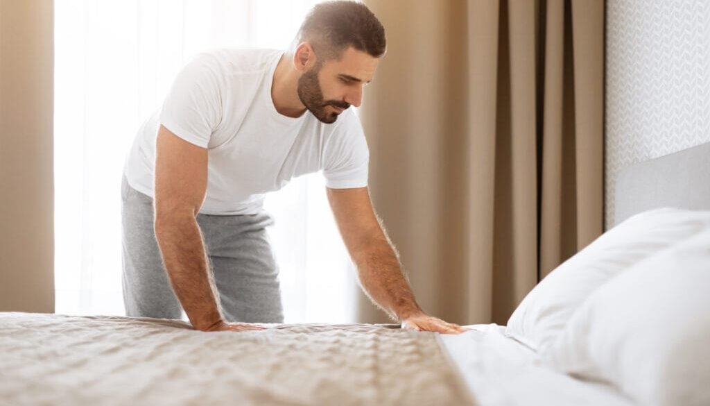 Man making bed in home.